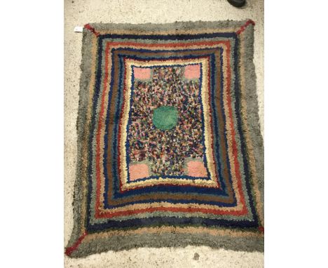 An early 20th Century rag rug, the central panel set with a green circular medallion on a multi-coloured ground, within a ste