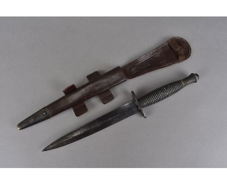 A Fairbairn Sykes dagger, having the metal ribbed handle and 17cm long double edged blade, marked with a broad arrow above a 