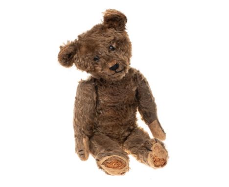 An early 20th century brown plush Teddy bear: with boot button eyes, stitched nose and mouth over a jointed body with humped 