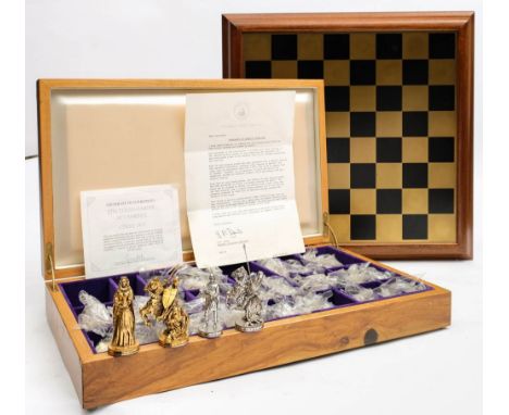 A cased Franklin Mint 'Tournament of Camelot' chess set and board: the cast pewter pieces electroplated in 22ct gold and silv