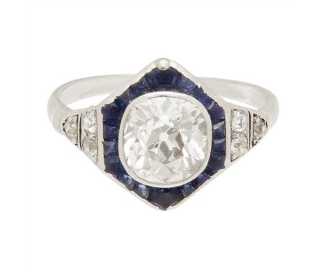 An early 20th century sapphire and diamond set cluster ring collet set with a cushion-cut diamond in a channel set border of 