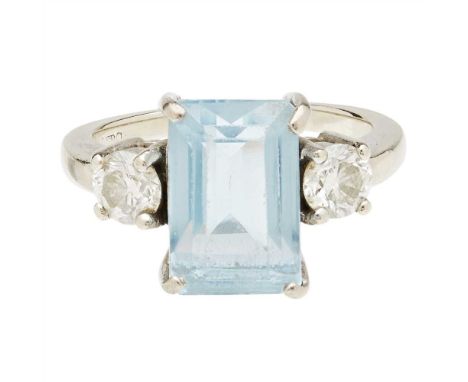 An aquamarine and diamond set ring claw set with a trap-cut aquamarine, flanked to either side by a round brilliant-cut diamo