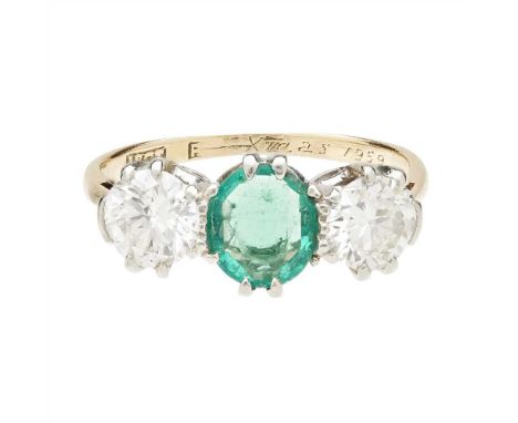 An emerald and diamond set three stone ring claw set with an oval-cut emerald, flanked to either side by a round brilliant-cu