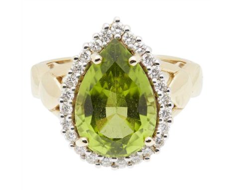 A peridot and diamond set cocktail ring claw set with a pear-shaped peridot in a border of round brilliant-cut diamonds, an 1
