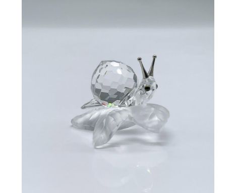 This enchanting snail is made from clear crystal, with metal antennae, and it is sitting on a frosted crystal leaf. This item