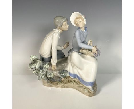 A glossy figurine of a seated man and woman, elegantly posed with graceful gestures. Lladro backstamp. Dimensions: 8.5"L x 8"