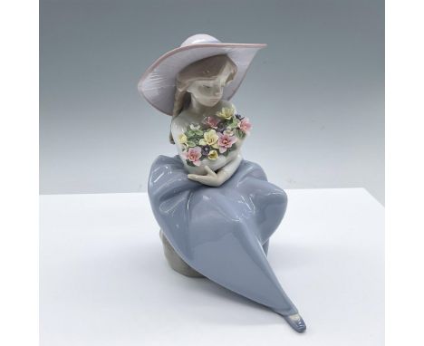A glossy figure of a young girl in a wide brim hat, cradling a flowers in her arms. Lladro backstamp. Artist: Antonio RamosIs