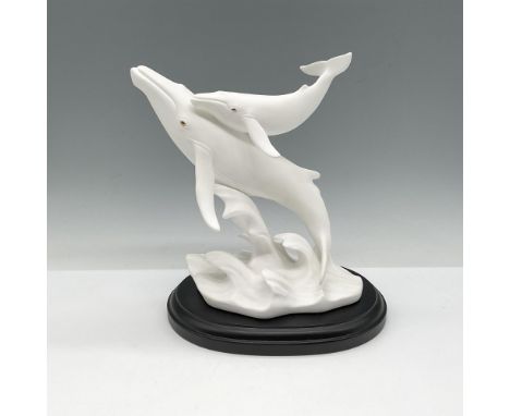 Hand crafted white bisque sculpture of mother and calf riding a wave. Lenox backstamp. This item has a brown wooden base incl