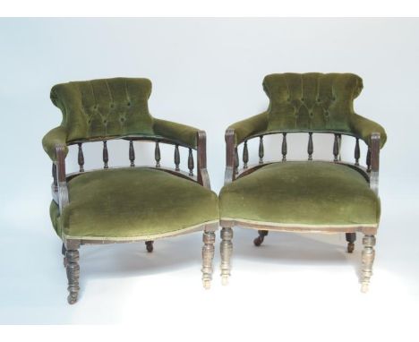 A pair of Victorian mahogany tub chairs, having button backs, upholstered panel with turned legs terminating on ceramic casto