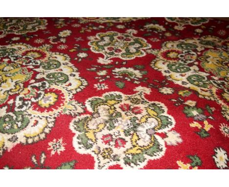 An Axminster Persian style bordered carpet, with stylised flower head motifs in green and yellow on a red ground, 280cm x 230