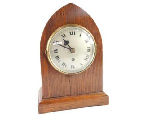 A mid 20thC oak lancet style mantel clock, having metallic dial with brass surround, Roman numerals and minute track with Tan