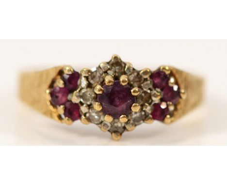 A 9ct gold ruby and diamond floral cluster ring with patterned band, M, 2.3g
