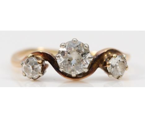 An unmarked 9ct gold three stone old cut diamond cross over ring, central diamond approx 0.40ct, estimated HI, P1/2, J, missh