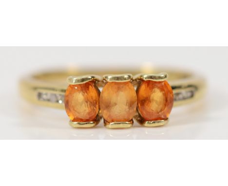 A 9ct gold orange gemstone three stone ring with diamond set shoulders, R, 2.3g
