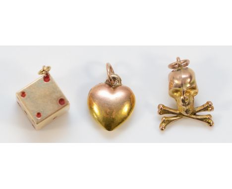 Three 9ct gold charms to include a skull and crossbones, a heart and a dice example, 2.4g