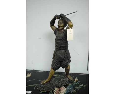 A 20th Century bronze model of a Samurai holding his sword aloft, dressed in period armour, raised on a naturalistic base, 49