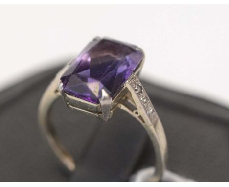 An amethyst ring, the rectangular facet-cut amethyst flanked by diamond set shoulders, the white metal shank stamped '18ct. &