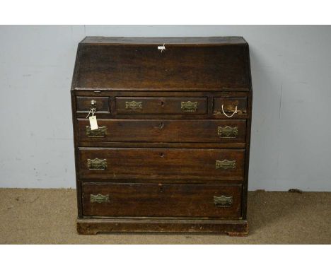 A George III oak bureau, the rectangular top above a fall front enclosing drawers and pigeonholes, above an arrangement of th
