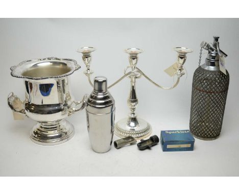 A vintage soda syphon; a chromium-plated cocktail shaker; a three-section candelabra; and a wine cooler.