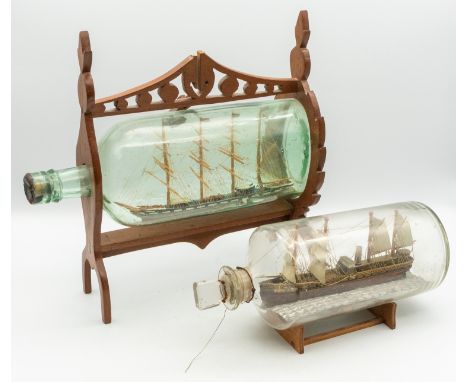 Two 19th century wooden models of Ship's in glass bottles; one encased in a light wooden frame of stylised shape, curved legs