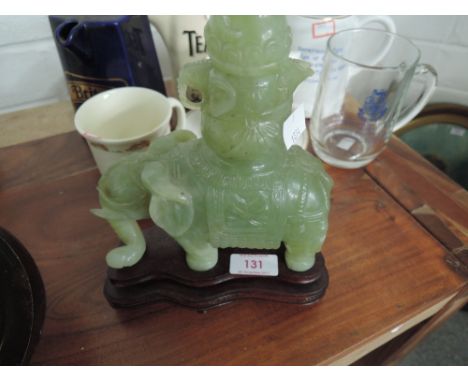 A glass elephant in the carved jade style on a wooden plinth