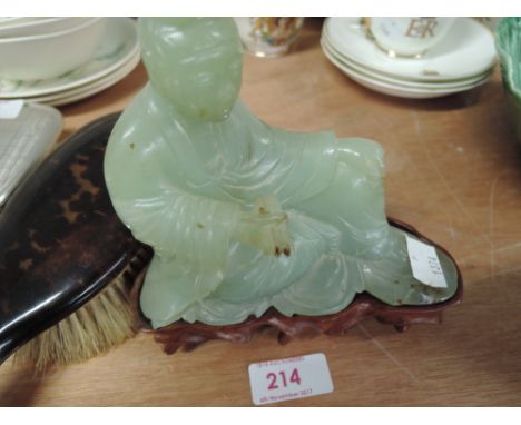 A carved figure jade stone with treen base depicting a Buddah like statue