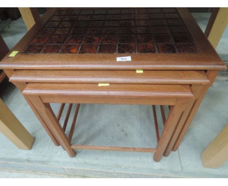A vintage teak nest of tables having rouge tile top