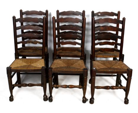 Set of six oak ladder back chairs with rush seats. Raised on turned tapering supports united by turned stretchers on pad feet