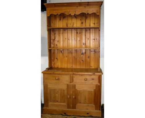 A contemporary two piece pine kitchen dresser. The upper section having a galleried top and two fixed shelves, the lower sect