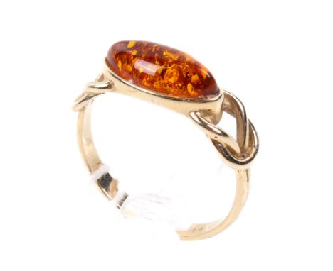 A yellow metal and amber ring. The band stamped '585', having interlocked shanks and set with an oval piece of amber, size Q/