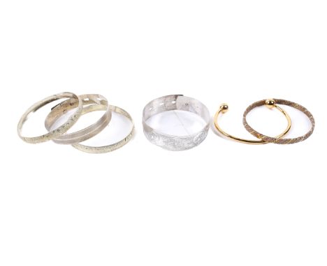 Five white metal bangles and a gilt metal bangle. Including a belt and torque example and others with pierced and engraved de