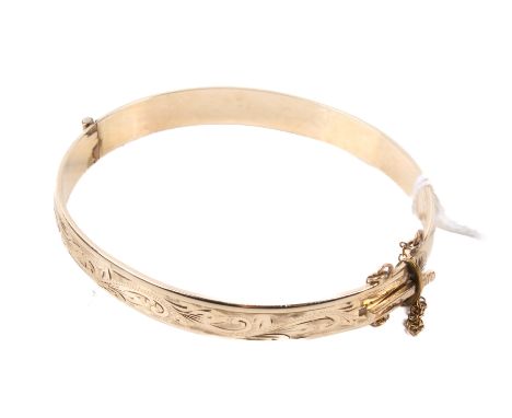A 9ct gold covered hinged bangle. One half with engraved scrolls, marked '9ct metal core P/S', with security chain. Gross wei