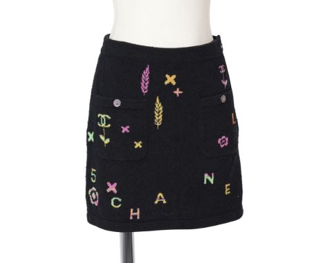 CHANEL, collection Prêt à Porter Printemps/Eté 2022. Mini Jupe en lainage bouclette noir à motifs multicolores.Directeur arti