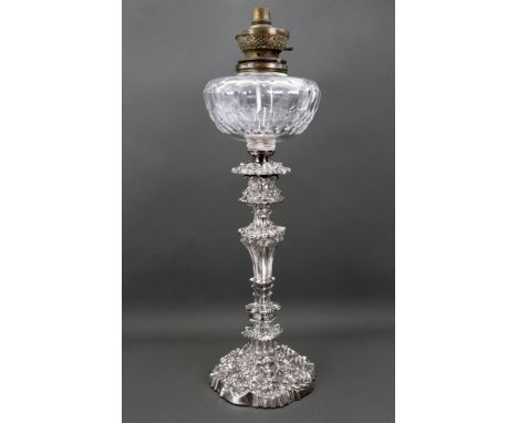 A late Victorian silver table oil lamp, marks rubbed, probably London 1897, with faceted glass reservoir, the rococo style ca