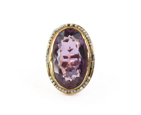 An Art Deco gold, amethyst, seed pearl and enamel ring, the oval mixed-cut amethyst within a seed pearl and enamel flower sur