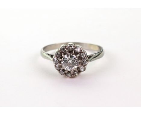 A white gold and diamond cluster ring, the central old-cut diamond approx. 0.40ct., in a 12-stone surround, between split-sho