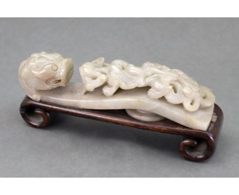 A Chinese celadon jade belt buckle, probably 19th century, carved with dragons head terminal, the shaft carved with a chilong