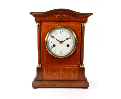 An Edwardian mahogany boxwood strung and foliate inlaid mantel clock, in an arched top pillared case, the white enamel dial w