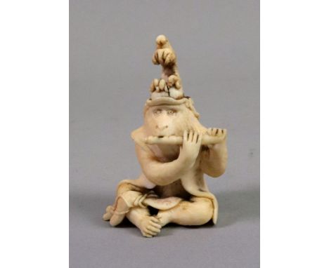 A Japanese carved ivory netsuke, Meiji, in the form of a seated ape playing a flute, 6.5cm high.