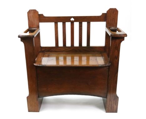 An Art Nouveau oak hall bench, the slatted back flanked by stick compartment arm rests, hinged compartment seat, 81cm wide x 