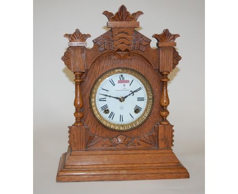 A late 19th century oak cased mantel clock by the Ansonia Clock Company of New York having an enamel dial with Roman numerals