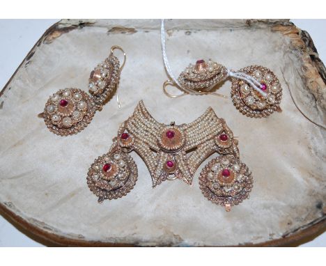 A 19th century Eastern yellow metal and seed pearl set garniture to include brooch and a pair of matching drop pendant earrin