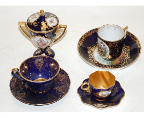 A small early 20th century Vienna porcelain twin handled urn and cover having a central floral painted panel on a dark blue g