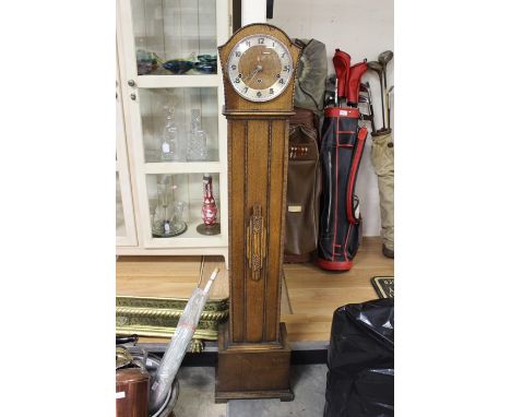 A 1930s oak eight day Grand Daughter clock, with three winder holes, Westminster chime, silvered chapter ring and Arabic nume