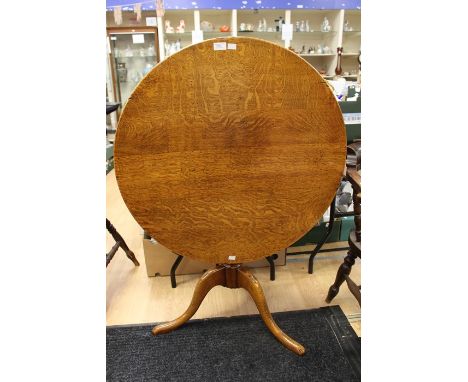 A George III style oak tilt-top tripod table, traditionally made, the circular top raised on a turned pedestal base, standing