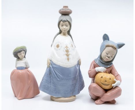 Three Nao figures of young girls, one with a pumpkin