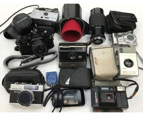 A collection of assorted cameras and lenses including Pentax MV1 with a Pentax M1:2 50mm lens, Pentax Vivitar 75-205mm lens, 