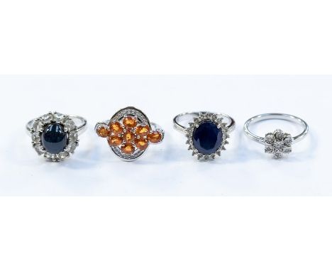 Four silver stone set rings to include a star sapphire and white topaz cluster ring, set to the centre3 with an oval sapphire