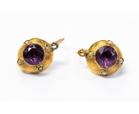 A  pair of yellow metal paste set stone earrings, possibly of Ethnic origin, circular hollow form set to the centre with purp