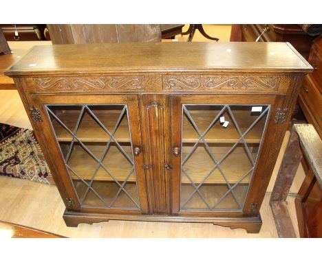 A 1970's oak glazed bookcase, Singer tredle sewing machine in oak work table, a mid 20th Century child's desk, light beech